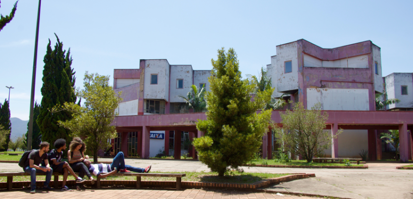 Foto aberta do campus, com o Centro de Convergência ao fundo e, no primeiro plano, estudantes sentados conversando